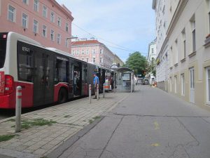 Eine Bushaltestelle in der gerade ein Bus steht. Ein Mann steigt ein. Foto von Maria Grundner