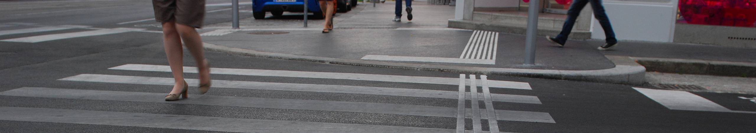 Eine Frau mit High Heels überquert an einem grauen Regentag die Straße. Foto von Gerd Götzenbrucker