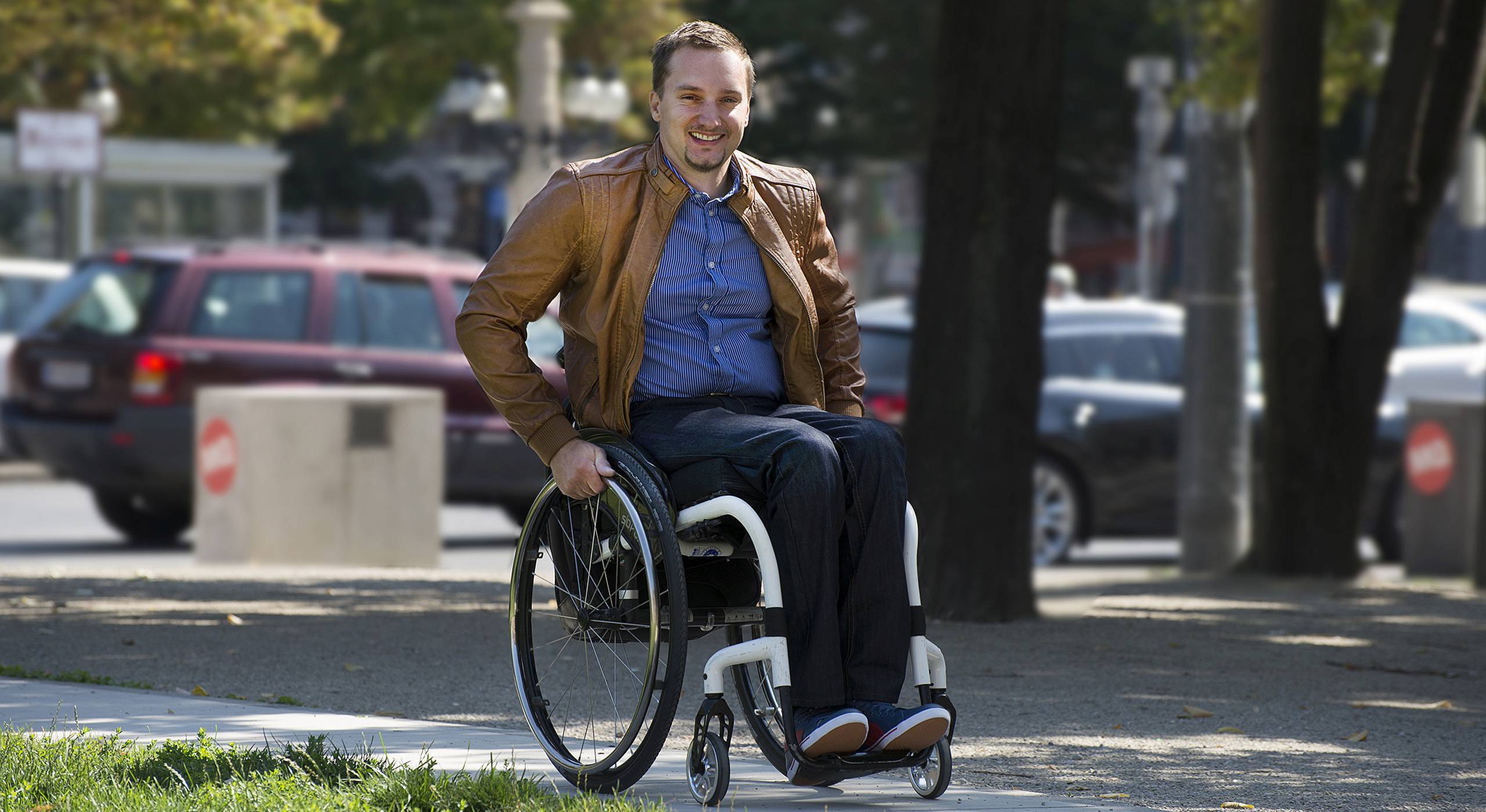 Ein Rollstuhlnutzer fährt durch einen Park in Wien. Foto von Ernst Grünwald