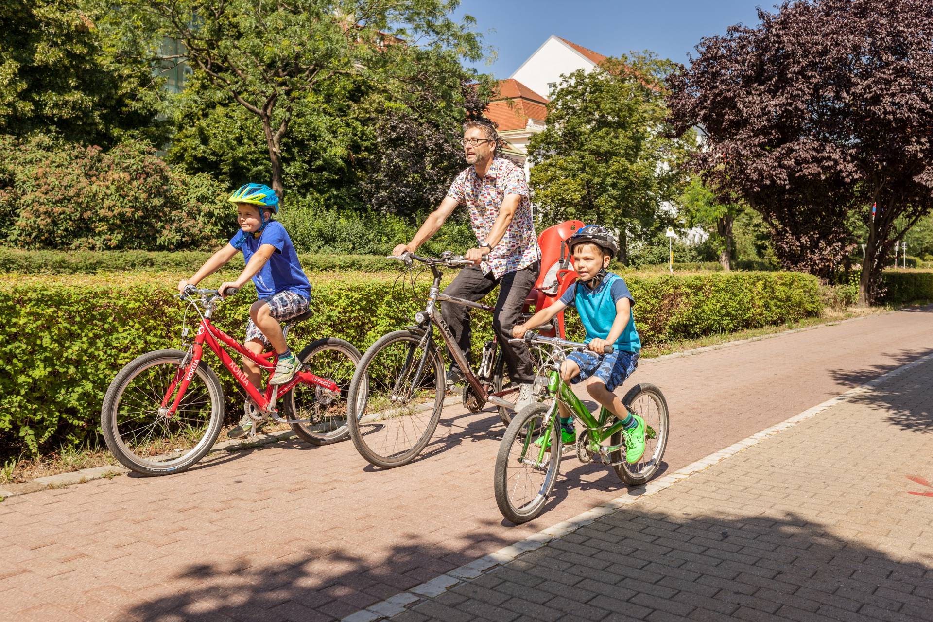 Ein Vater und seine beiden Söhne fahren gemeinsam Fahrrad. Foto: Stephan Doleschal