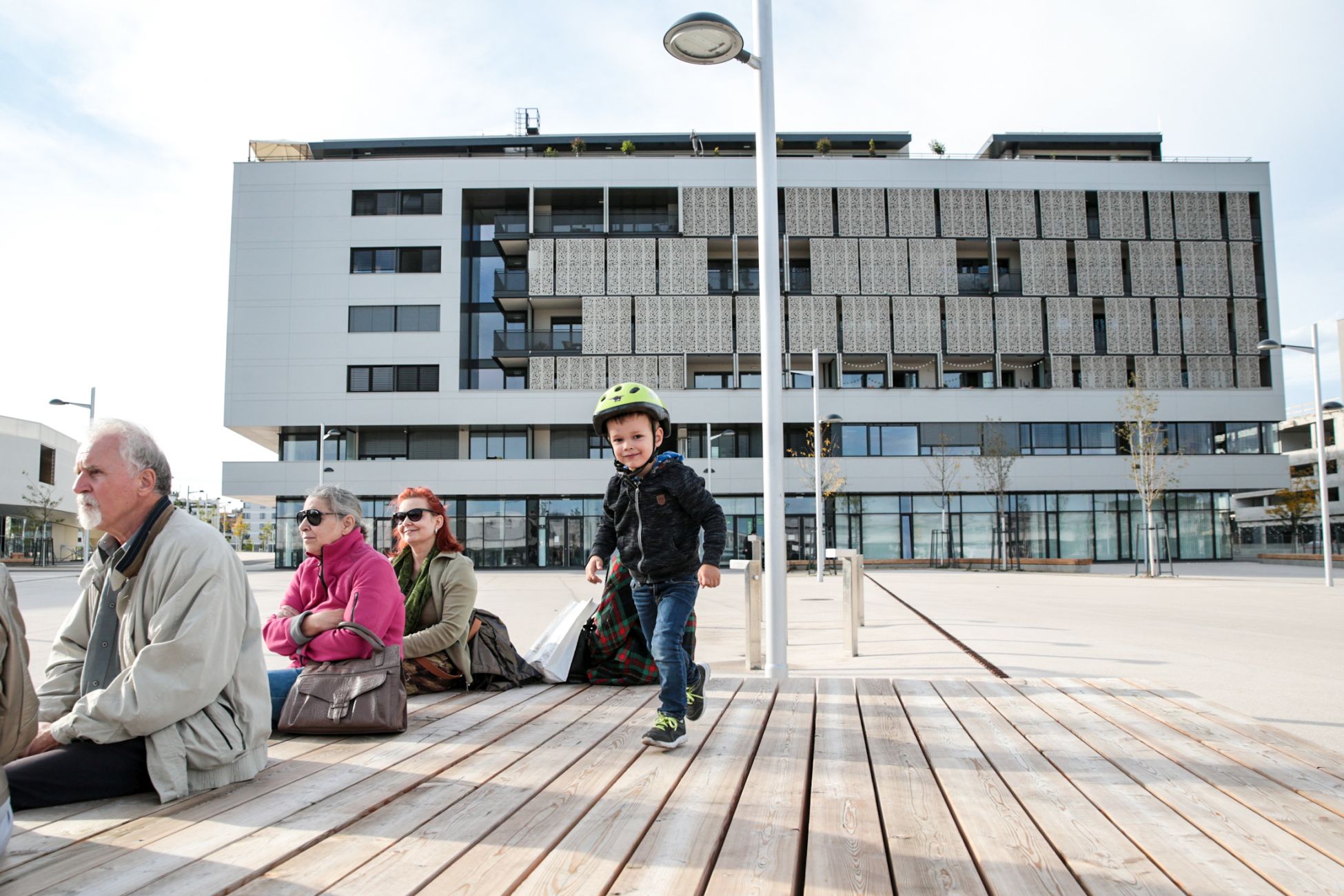 Sitzmöbel in der Seestadt Aspern. Ein kleiner Bub, zwei Frauen und ein Mann sitzen darauf. Foto: Mobilitätsagentur Wien/Christian Fürthner