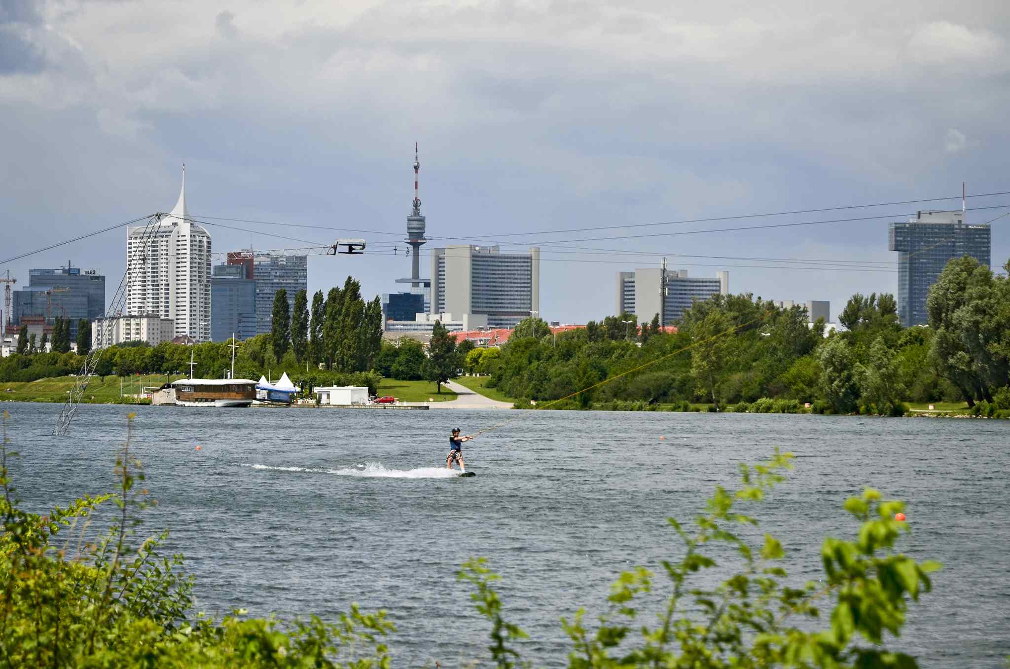 Wakeboardfahrer am Wakeboardlift, im Hintergrund die Skyline der Donaustadt