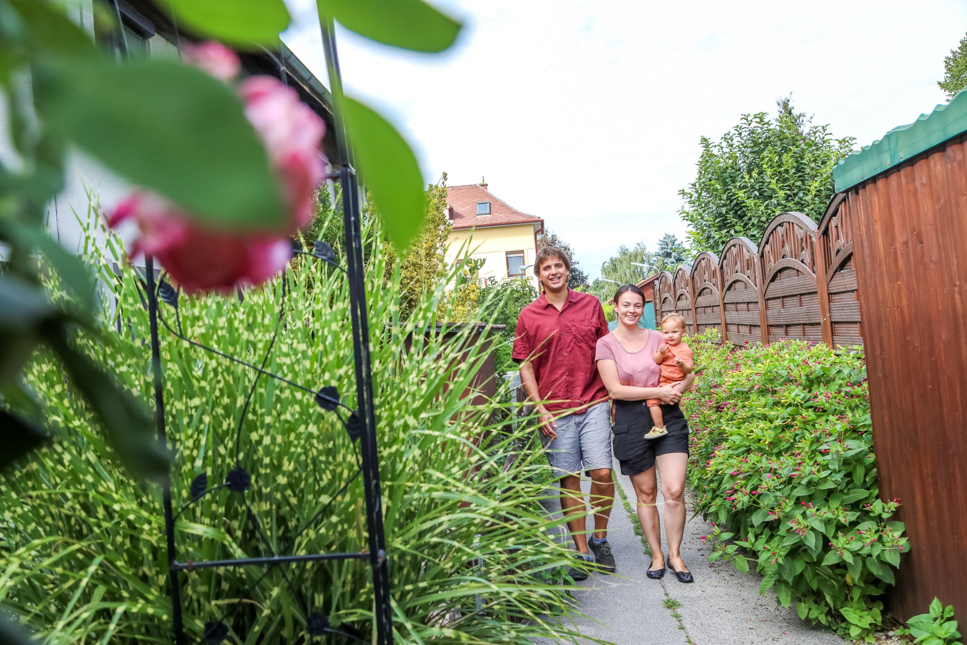 Dreiköpfige Familie auf einem schmalen Weg mit viel Pflanzen