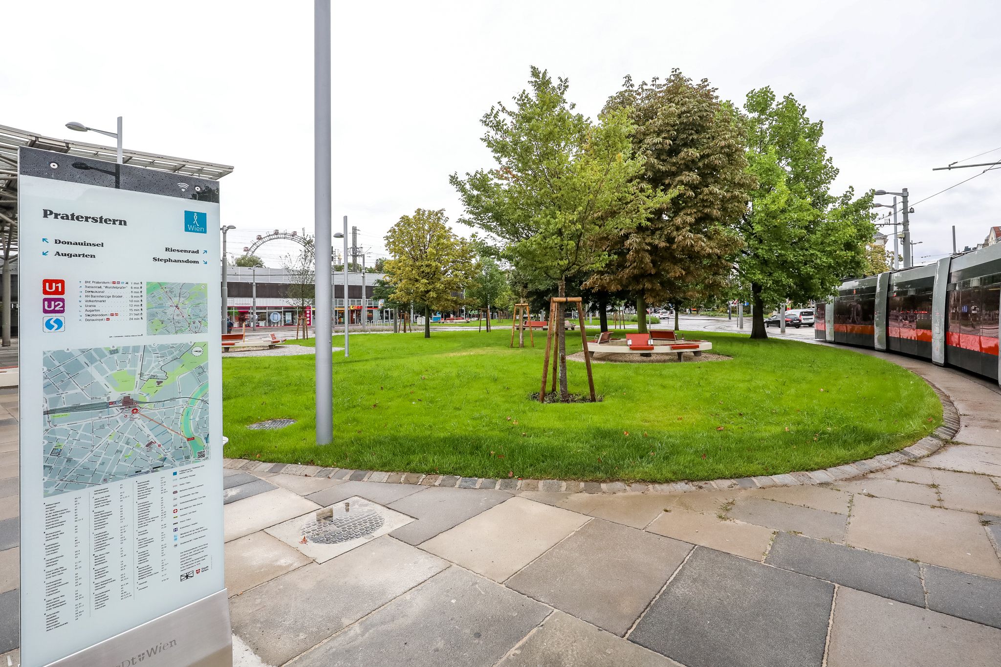 Neuer Vorplatz am Praterstern: Im Vordergrund eine Orientierungsstele, im Hintergrund Rasen, Sitzplätze und Bäume