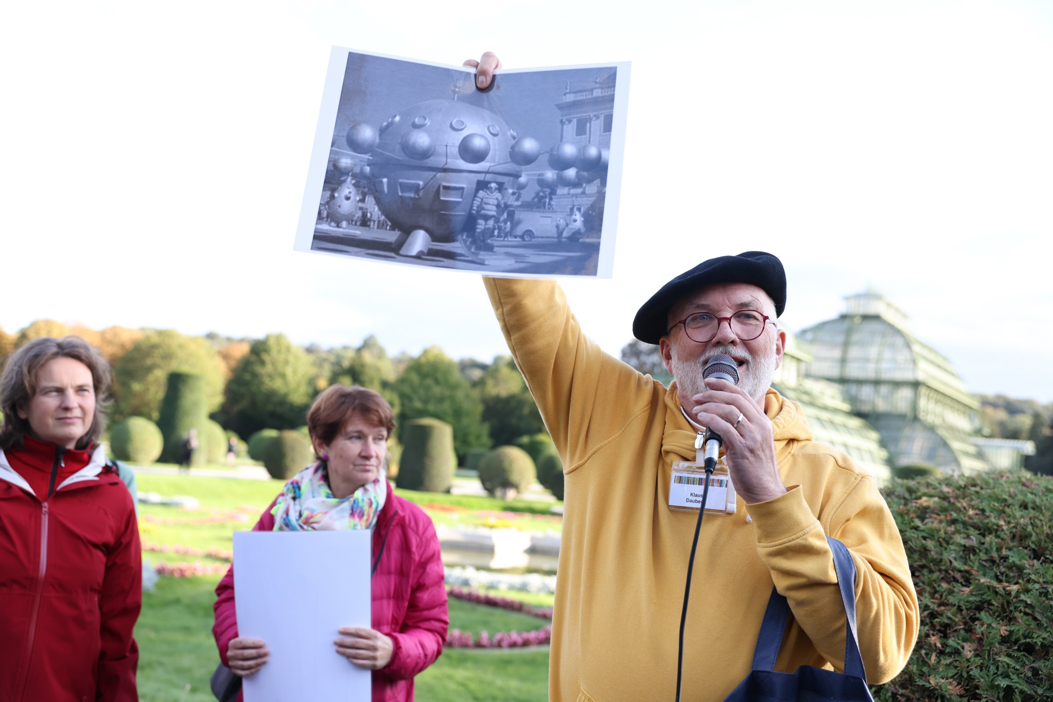 Klaus Daubeck im Schönbrunner Schlosspark, er hält ein Bild des Films "1. April 2000" hoch