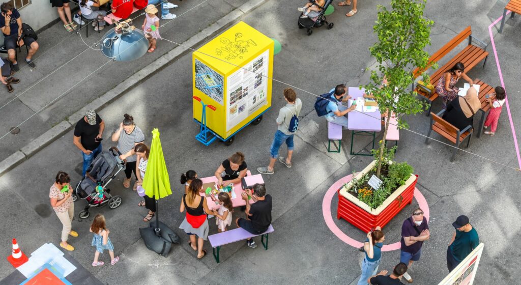 Supergrätzl von oben, zu sehen: Besucher:innen am Bänken, ein Infowagen etc.