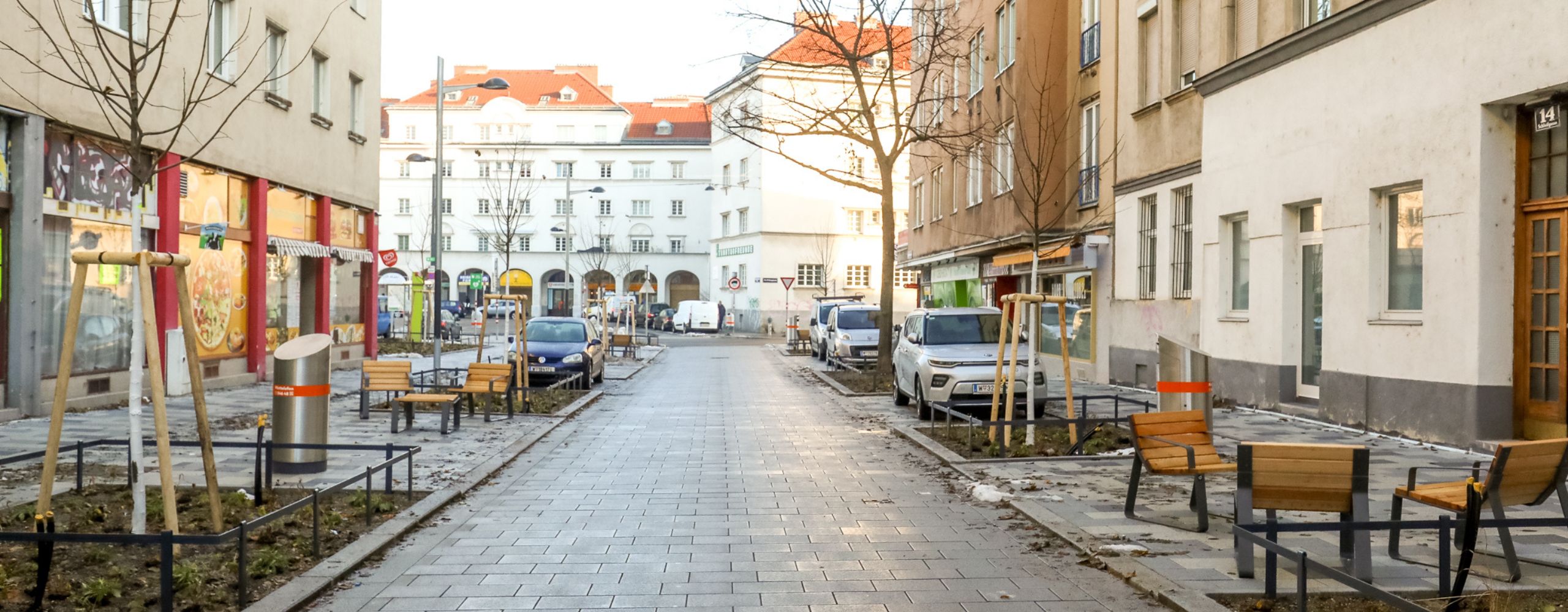 neue Schleifgasse mit Blick auf den Schlingerhof. Links und rechts sind neue Bäume und Sitzgruppen zu sehen.